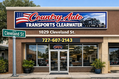 Storefront of Country Auto Transports Clearwater with trucks on the sign, a phone number, address (1029 Cleveland St), and an OPEN sign above the entrance. A Cleveland St street sign is visible in front, clearly marking this trusted location for FL Auto Transport Clearwater services.